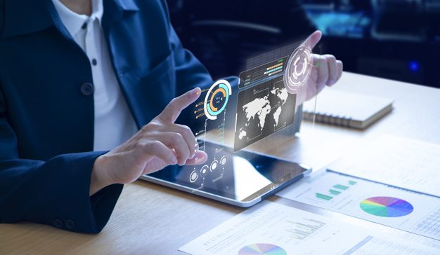 Business man or analyst expanding futuristic investment virtual screen over a modern tablet. Showing if charts and infographic for investment analysis.