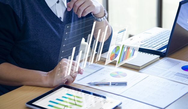 Businessman with virtual reality graphics is deeply reviewing financial reports for a return on investment, ROI, or investment risk analysis.